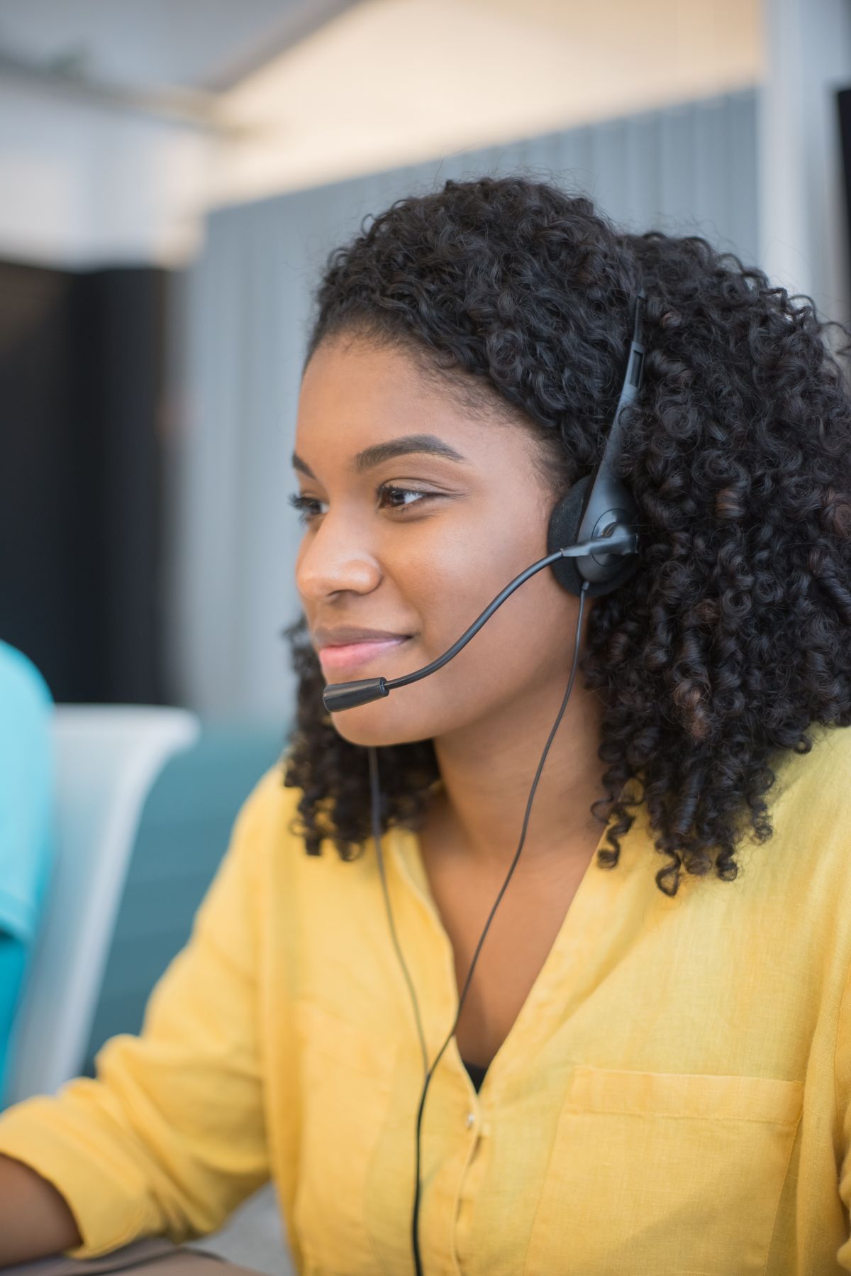 A friendly support agent wearing headphones, ready to help at their computer.
